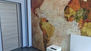 A room with a large world map on the wall, a door, and a small white cabinet. - B&B Vecchia Darsena - Your home on the old port - Room "the rudder" (Augusta)