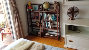 Une chambre à coucher avec un lit, une bibliothèque, un globe terrestre et un ventilateur.