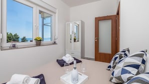 A hotel room with a large window, a wardrobe, a bed with a striped pillow, and a tray with a bottle and glasses. - Gorgeous apartment in Rijeka with WiFi (Rijeka)