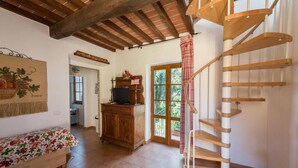 A spacious living area with a wooden staircase, a wooden cabinet, and a television.