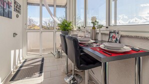 A dining area with a table set for four, a black leather chair, a potted plant, and a view of the sky through large windows. - Stunning home in Malinska with heated swimming pool (Malinska)