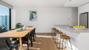 Et moderne køkken med et træspisebord, barstole og en hvid bordplade.