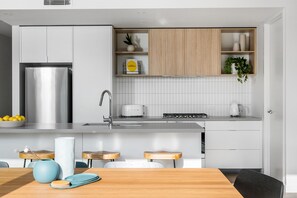 A modern kitchen with a stainless steel refrigerator, a toaster, and a kettle on the countertop. - Axel Apartments 203 The Bonfield (Glen Iris)