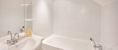 A modern bathroom with a white sink, a bathtub, and a mirror.