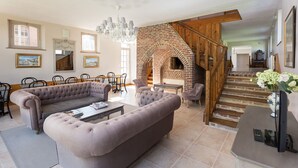 A spacious living room with a large sectional sofa, a fireplace, and a staircase leading to an upper level. - CHARMING ALL COMFORT gîte near the Baie de Somme (Aigneville)