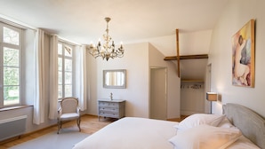 A bedroom with a large bed, a chandelier, a chair, a dresser, and a painting on the wall. - CHARMING ALL COMFORT gîte near the Baie de Somme (Aigneville)