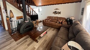 A cozy living room with a wooden ceiling, a fireplace, a sofa, and a staircase. - Lakefront Chalet - Badwater Lodge - Gorgeous Lake Views (Florence)