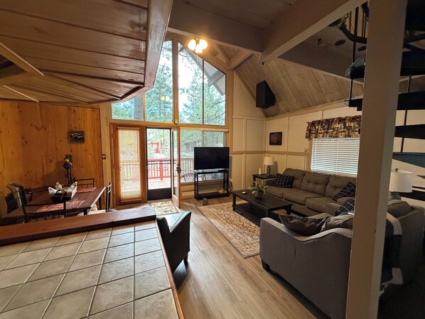 A spacious living area with a dining table, sofa, and a television. - Dog Friendly Cute cabin on quiet lot with lots of pines. (Munds Park)