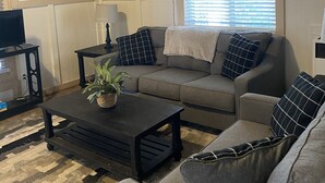 A cozy living room with a sofa, coffee table, and a television.