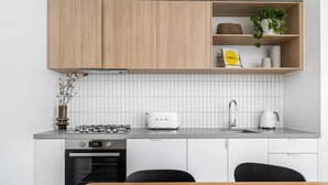 Eine moderne Küche mit weißen Schränken, einem Gasherd, einem Toaster und einer Spüle.