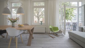 Un espace repas lumineux, avec une table en bois, des chaises blanches et un vase rempli de fleurs.