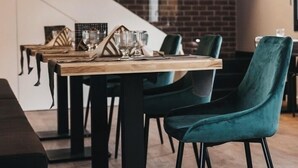 A modern dining area with wooden tables, black metal chairs, and a brick wall backdrop. - &Tales Suites - Óbidos (Obidos)