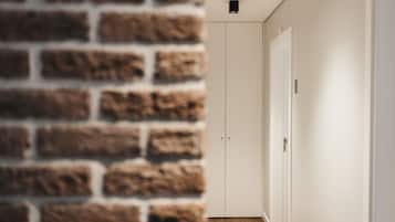 A hallway with a brick wall on one side and a white door on the other.