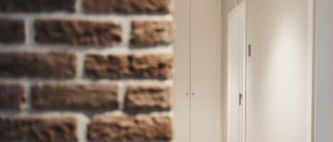 A hallway with a brick wall on one side and a white door on the other.