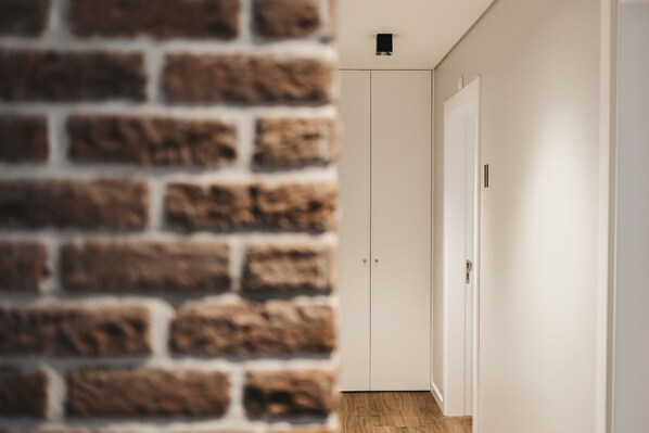 A hallway with a brick wall on one side and a white door on the other. - &Tales Suites - Óbidos (Obidos)
