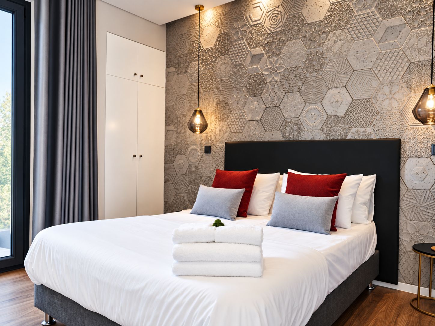 A modern bedroom with a large bed, a geometric patterned wall, and a window with curtains.