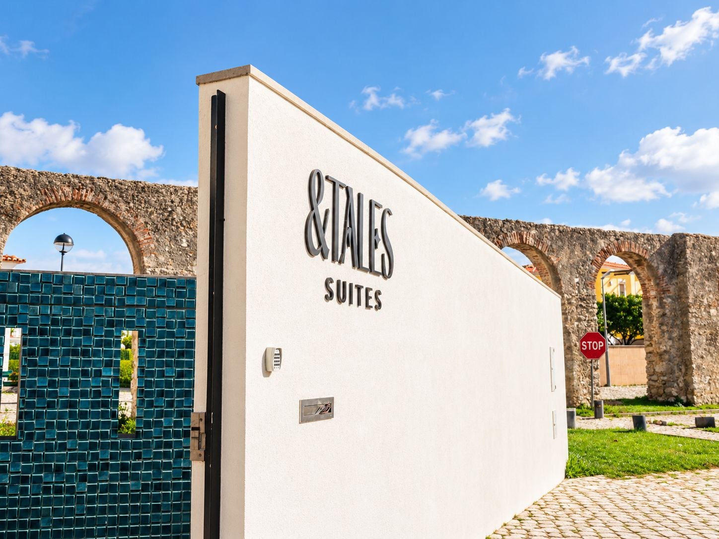 A building with a sign reading 'TALLES SUITES' and a stone archway in the background.