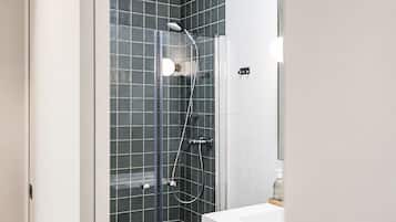 Une salle de bain avec une douche à parois de verre, un lavabo blanc et un miroir.