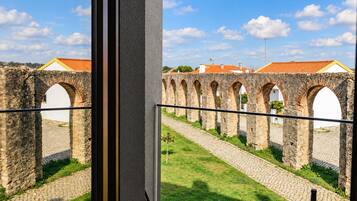 A balcony with a view of a historic stone bridge and buildings with red-tiled roofs.
