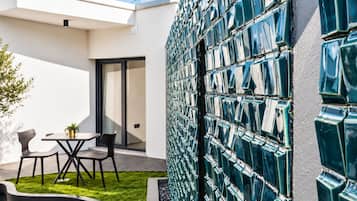 Un espace extérieur moderne aménagé avec une table et des chaises, une petite plante en pot et une pelouse bien entretenue.