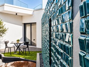 A modern outdoor seating area with a table and chairs, a small potted plant, and a well-maintained lawn. - &Tales Suites - Óbidos (Obidos)