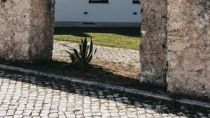 A modern building with a white facade and a large arched window framed by stone walls. - &Tales Suites - Óbidos (Obidos)