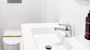 Un baño con lavamanos blanco, grifo cromado y un inodoro.