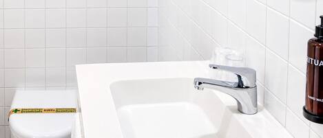 Un baño con lavamanos blanco, grifo cromado y un inodoro.