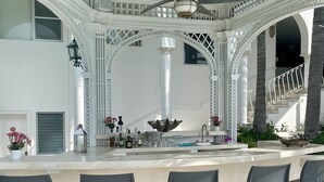 Un espace bar doté d’un comptoir blanc, de chaises noires et d’un plafond décoratif.