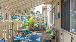 Un patio al aire libre con un toldo a rayas, muebles de mimbre y un letrero que dice 'The Ocean Fixes Everything'.