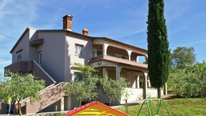 A house with a balcony, a playhouse, and a swing set in the yard. - Apartment in Krnica Near Beach & BBQ (Marcana)