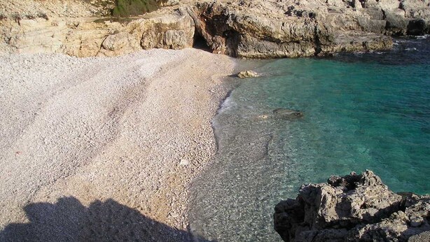 A rocky beach with clear turquoise water and a rocky cliff in the background. - Apartment in Krnica Near Beach & BBQ (Marcana)