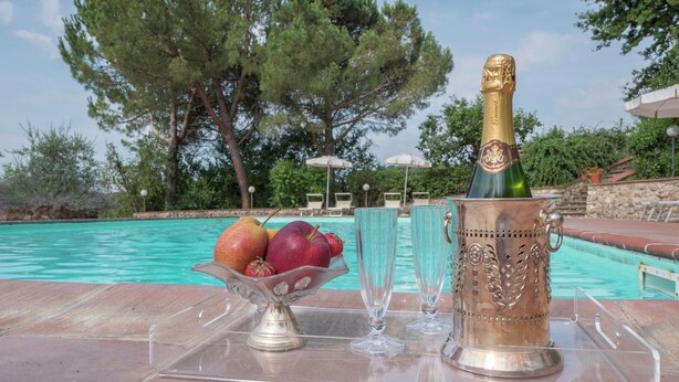 A poolside setting with a champagne bottle, fruit bowl, and glasses on a clear tray. - Holiday Home for 8 Guests (Siena)