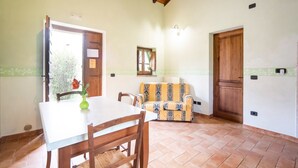 A dining area with a table and chairs, a sofa, a wooden ceiling, and a tiled floor. - Farmhouse in Citta di Castello With Pool (Città di Castello)