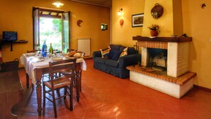 A dining area with a table set for four, a sofa, and a fireplace. - Attractive Mansion With Pool (Cortona)
