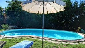 A swimming pool with a surrounding grassy area, a lounge chair, and an umbrella. - Attractive Mansion With Pool (Cortona)