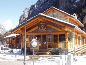 A wooden mountain lodge with a stone facade, a sign reading 'Brasserie Siride,' and a snow-covered landscape.
