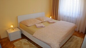 Une chambre à coucher avec un lit, des oreillers, une table de chevet et une lampe.