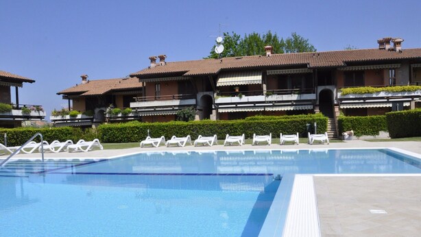 A swimming pool with lounge chairs and a tiled deck. - Holiday Home Lazise Near Lake and Gardaland (Lazise)