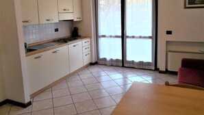 A kitchen with white cabinets, a tiled floor, and a sliding glass door. - Holiday Home Lazise Near Lake and Gardaland (Lazise)