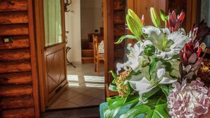 Un intérieur en bois avec une porte en bois donnant sur un escalier. On aperçoit un arrangement floral au premier plan.