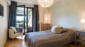A bedroom with a bed, a chair, a dresser, a lamp, and a ceiling light. - Apartment Krakow Near Wawel Castle (Kraków)