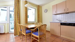 A compact kitchen with a dining area, featuring a Bosch dishwasher, wooden cabinets, and a window with curtains. - Ferienhaus in Willingen mit Skilift in der Nahe (Willingen)