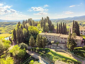 Surrounded by lush greenery and cypress trees, this traditional building offers a serene and picturesque setting.