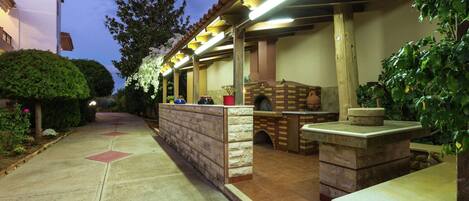 An outdoor patio area with a brick oven, stone seating, and potted plants.