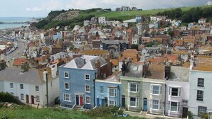 A coastal town with a mix of residential buildings, some with bay windows and a prominent hill in the background. - Lodge in Appledore Near Camber Sands Beach (Romney Marsh)