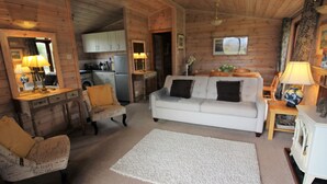 A cozy log cabin interior with a living room, a dining area, and a kitchen. - Lodge in Appledore Near Camber Sands Beach (Romney Marsh)