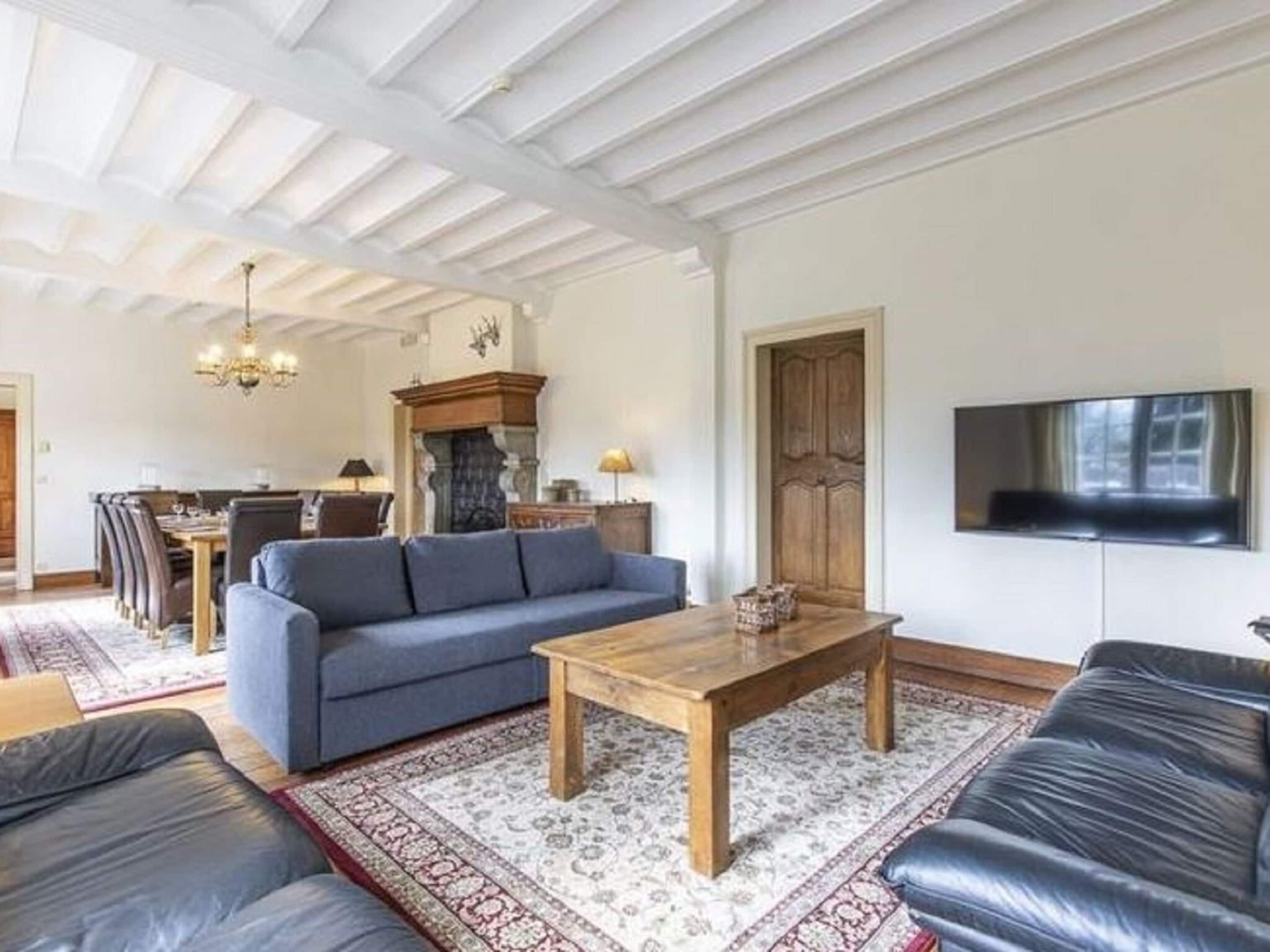 A living room with a sofa, a coffee table, a TV, and a fireplace.