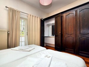 A hotel room with two beds, a bathroom with a mirror, and a large wooden wardrobe. - Luxurious Holiday Home in Érezée with Hot Tub (Erezee)