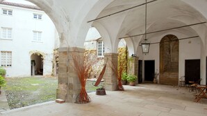 An interior courtyard with stone arches, potted plants, and a tiled floor. - A Castle Stay in Wine Country (Rocca Grimalda)
